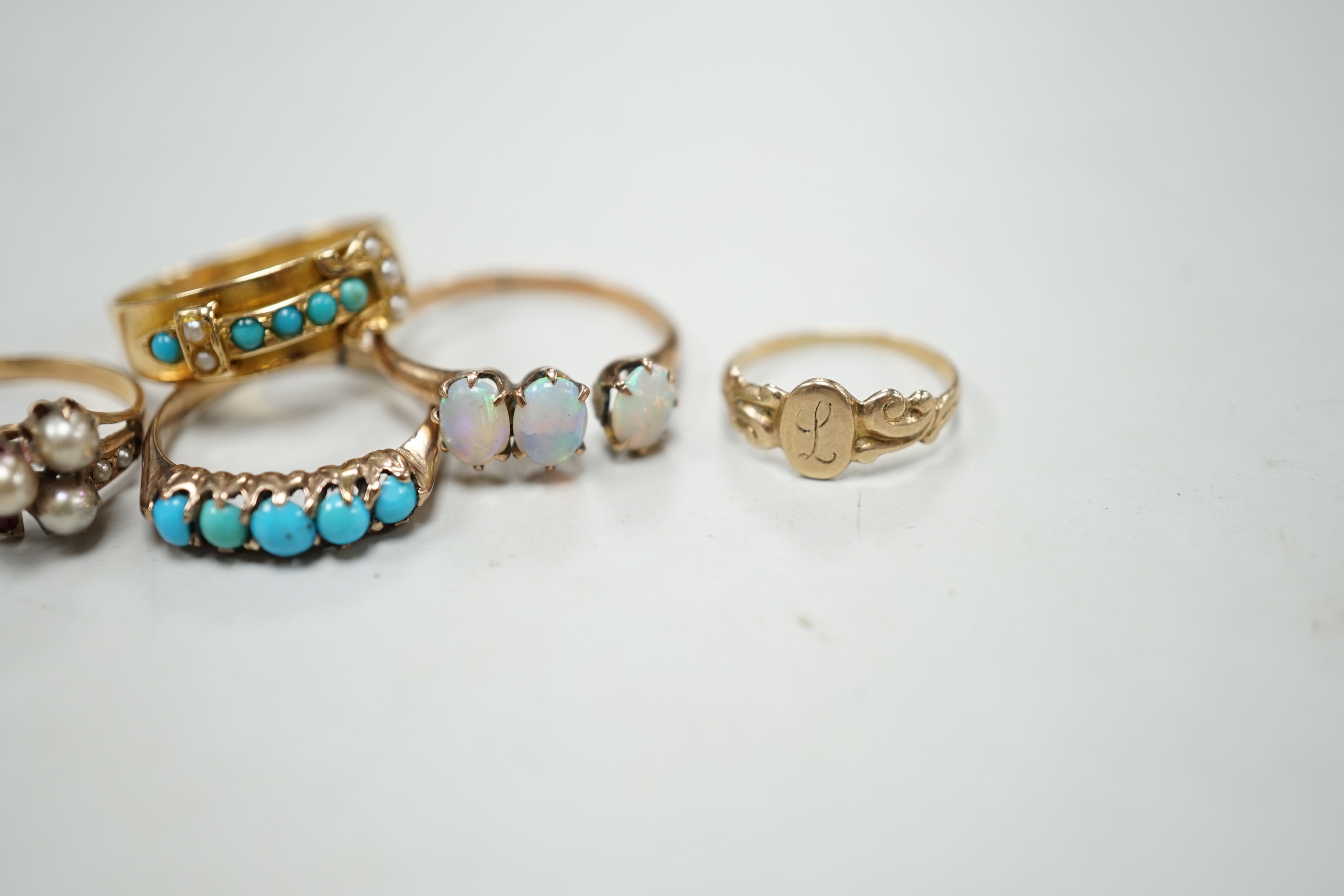 A late Victorian 18ct gold, turquoise and seed pearl set buckle ring, size P and four other yellow metal rings including gem set, gross weight 9 grams (a.f.).